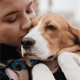 Close-up of woman cuddling her adorable puppy, emphasizing pet love and grooming expertise.