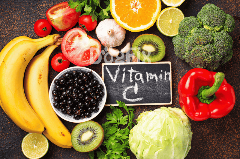 Colorful array of fruits and vegetables rich in Vitamin C on a dark background.