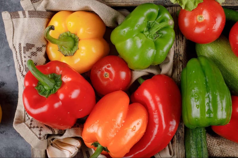 Assorted fresh red, yellow, and green bell peppers on rustic fabric.