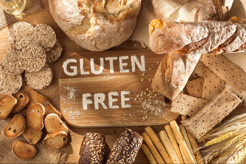 Gluten-free bread and bakery products displayed on a wooden surface, emphasizing gluten-free options.