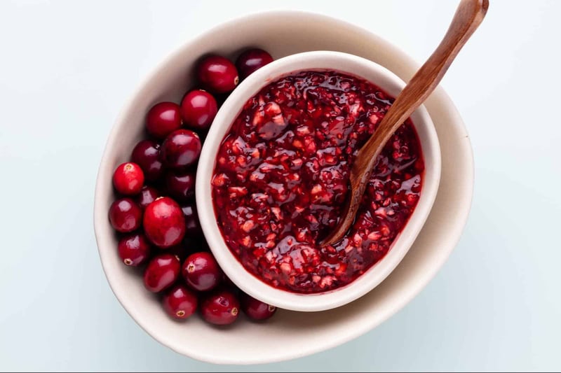 Fresh cranberry berry jam with a wooden spoon, served in a white bowl.