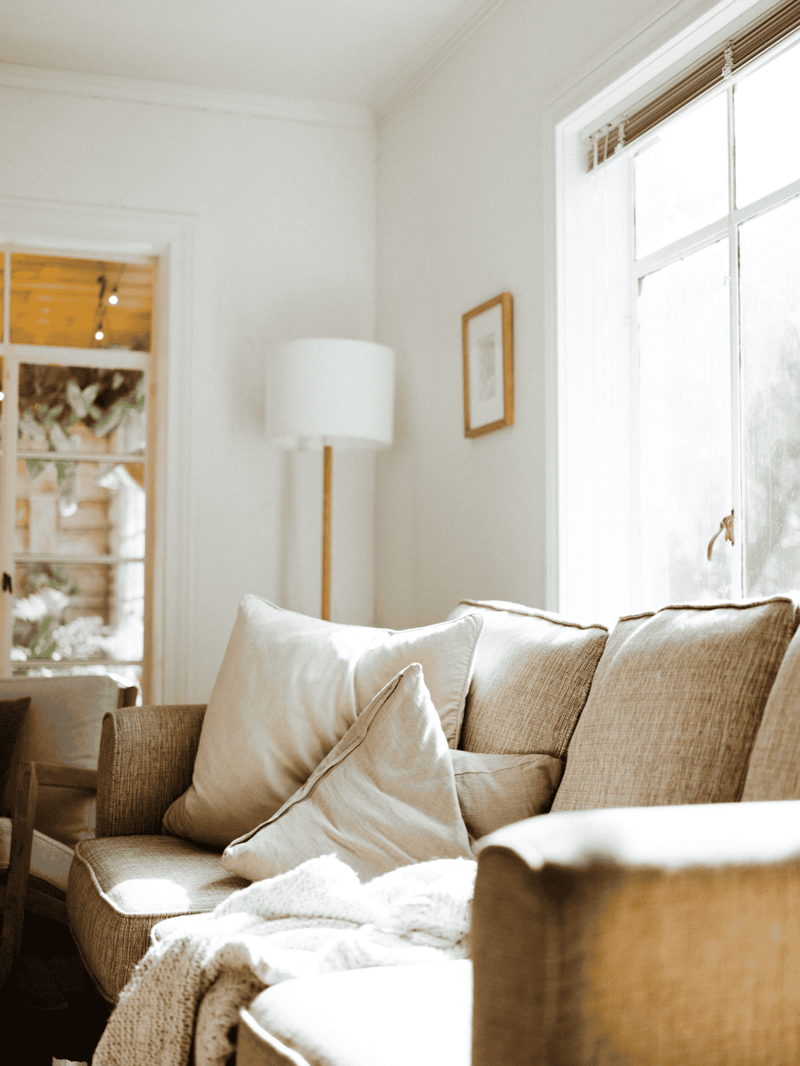 Comfortable beige sofa with pillows in a bright, inviting living room setting.