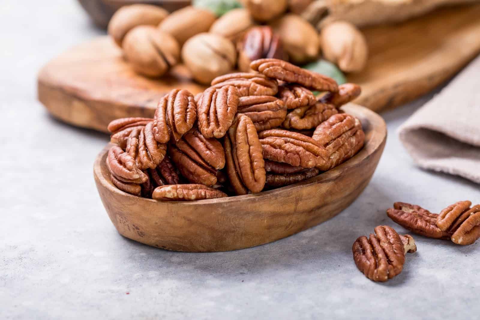 Healthy dog-friendly nuts like pecans and walnuts in wooden bowls.