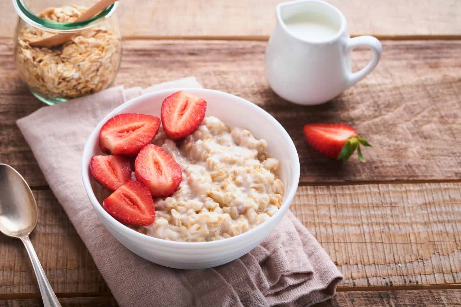 Bright strawberry oatmeal breakfast with fresh strawberries and milk in a white bowl.