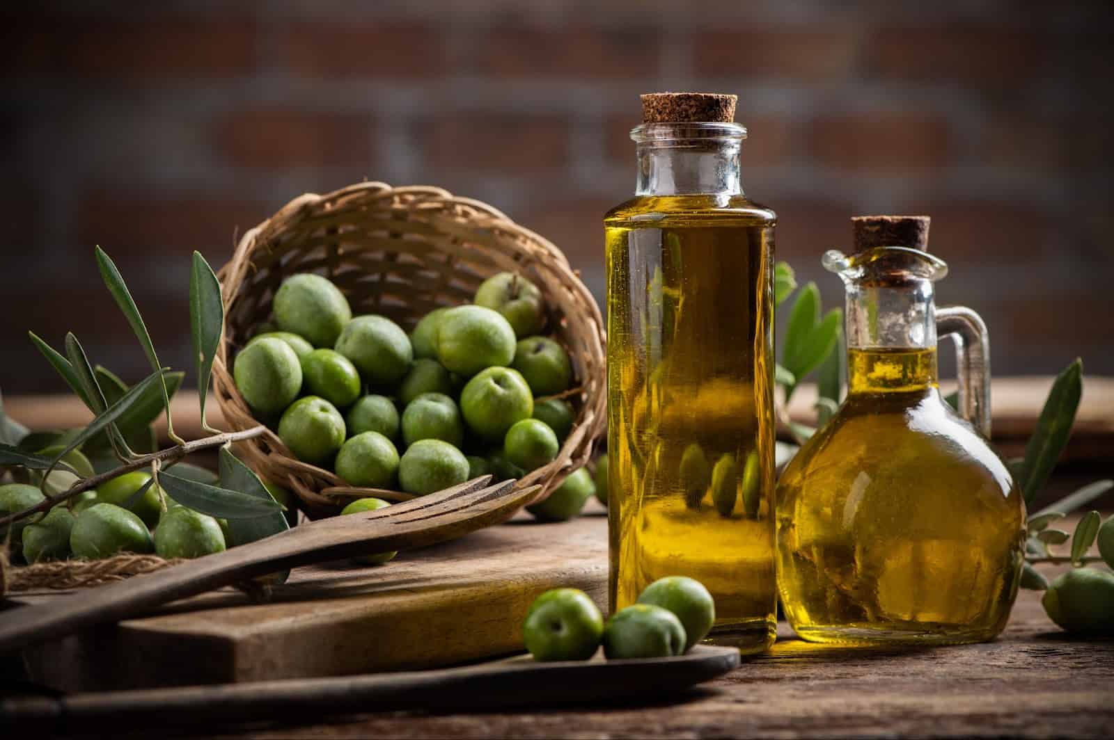 Olive oil and fresh green olives on a rustic wooden table, highlighting natural ingredients for dog-friendly diets.