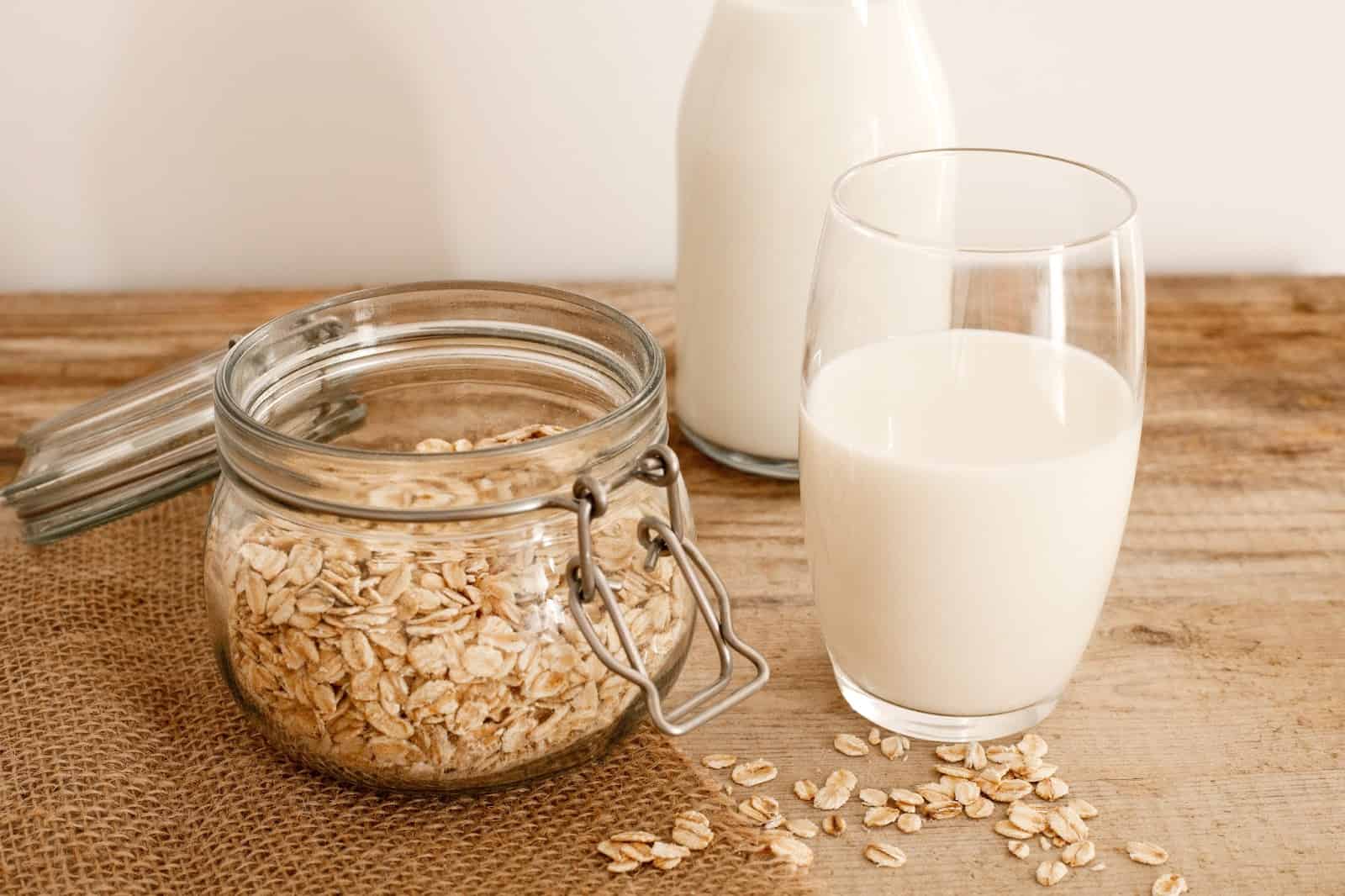 Alt text: Fresh oat milk poured into a glass with oats and a jar, natural dog-friendly milk alternative.