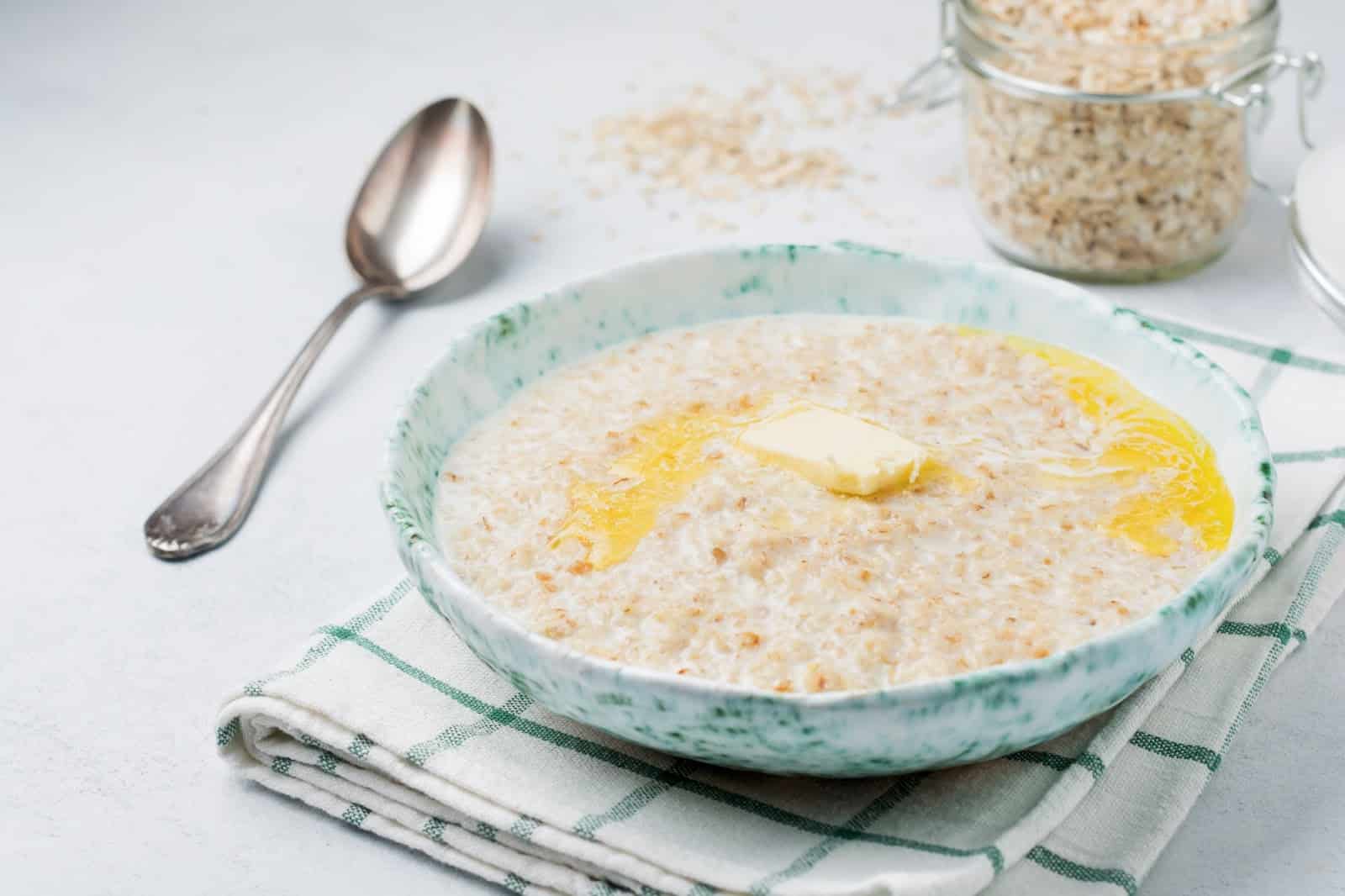 Healthy dog meal with oatmeal and butter in a ceramic bowl.