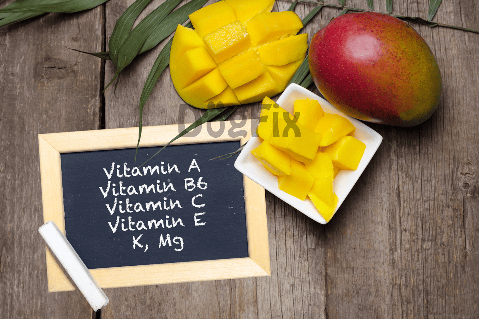 Healthy mango fruit with chopped cubes, whole mango, and chalkboard displaying vitamins for dogs.