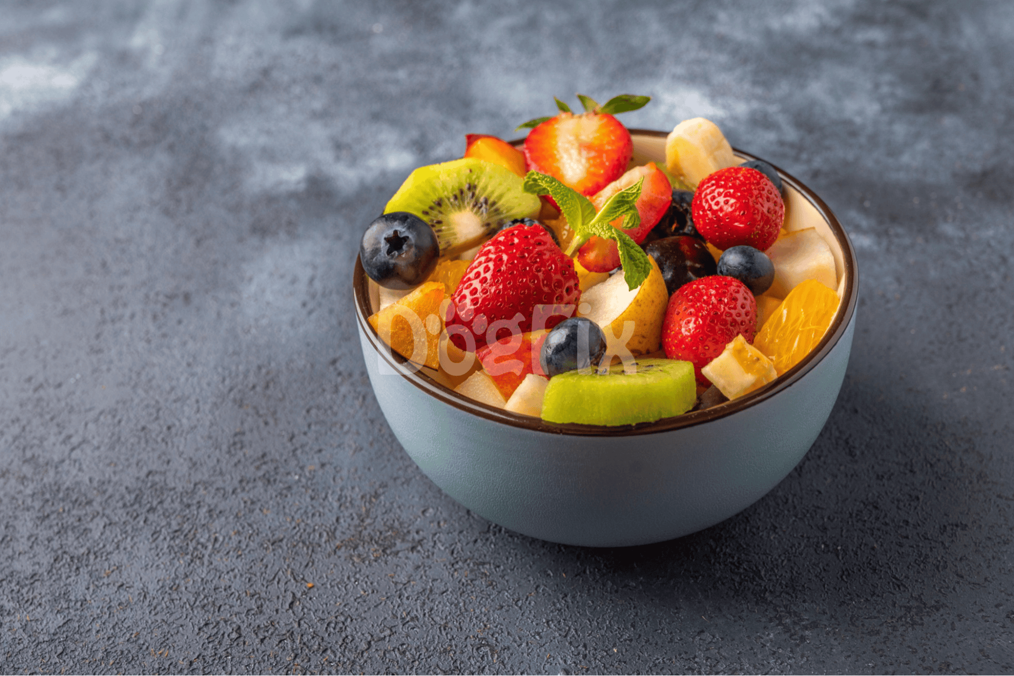 Healthy fruit salad with strawberries, blueberries, kiwi, and oranges for dogs' nutrition.