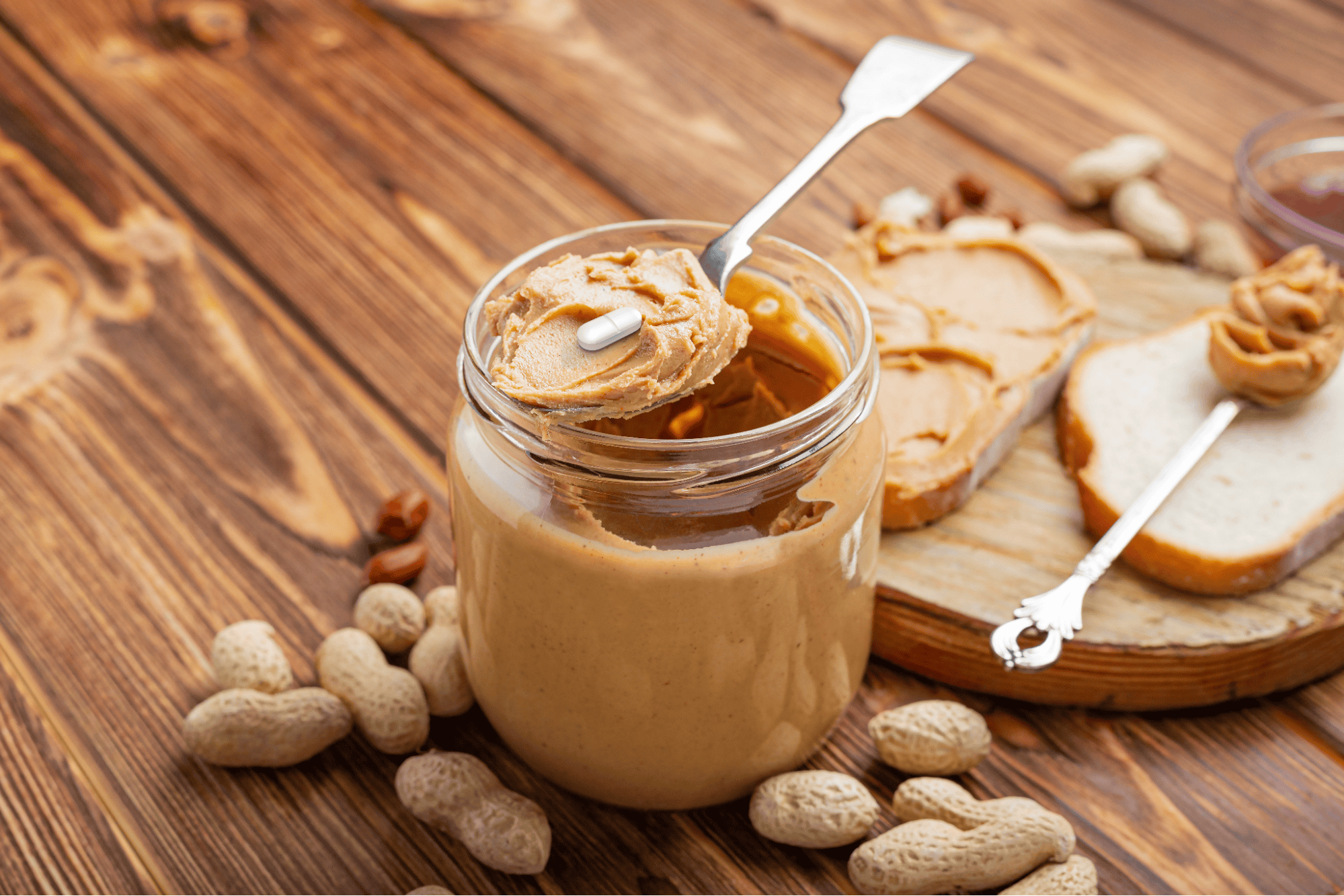 Peanut butter with a pill on a spoon, natural, healthy treat for dogs, on a wooden table.