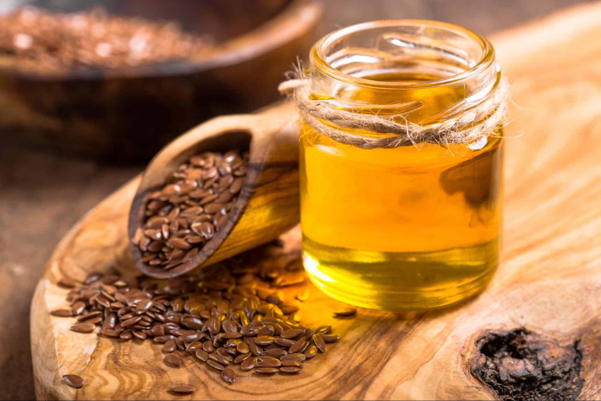 Healthy flaxseed oil in a glass jar on a rustic wooden surface.