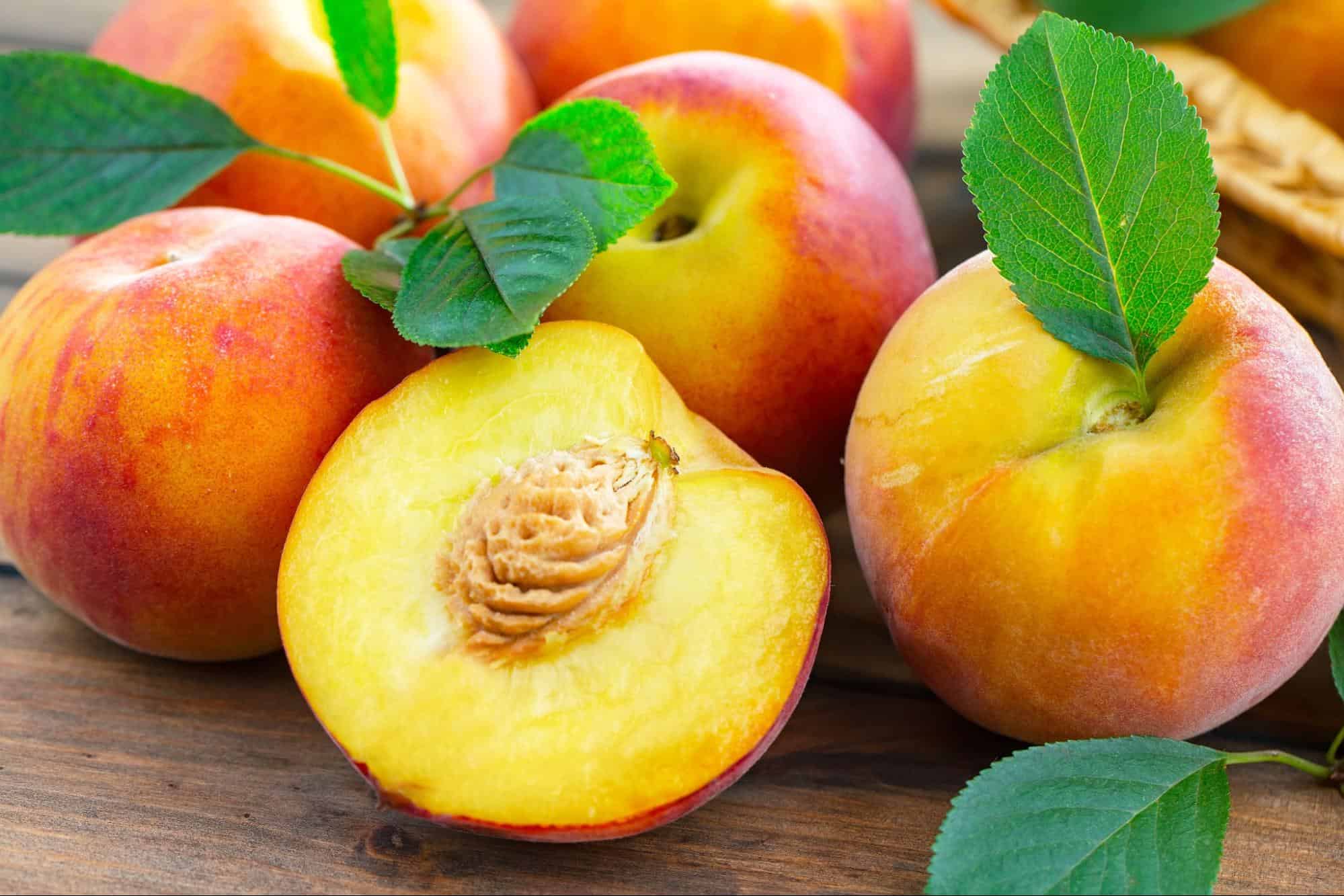 Fresh peaches with vibrant colors and green leaves, perfect for healthy snacks or desserts.