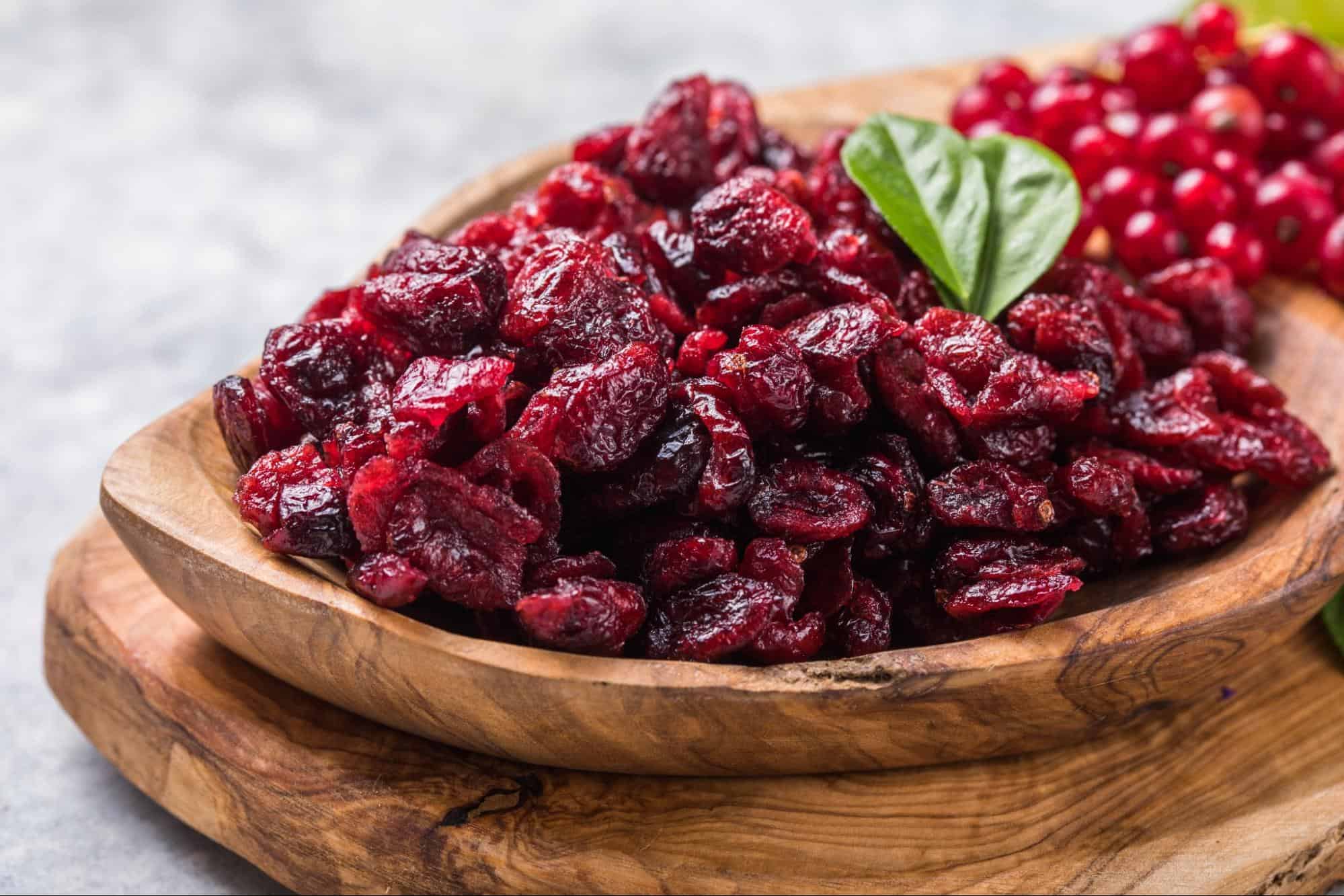Vivid image of dried cranberries garnished with a basil leaf, perfect for healthy snacking.