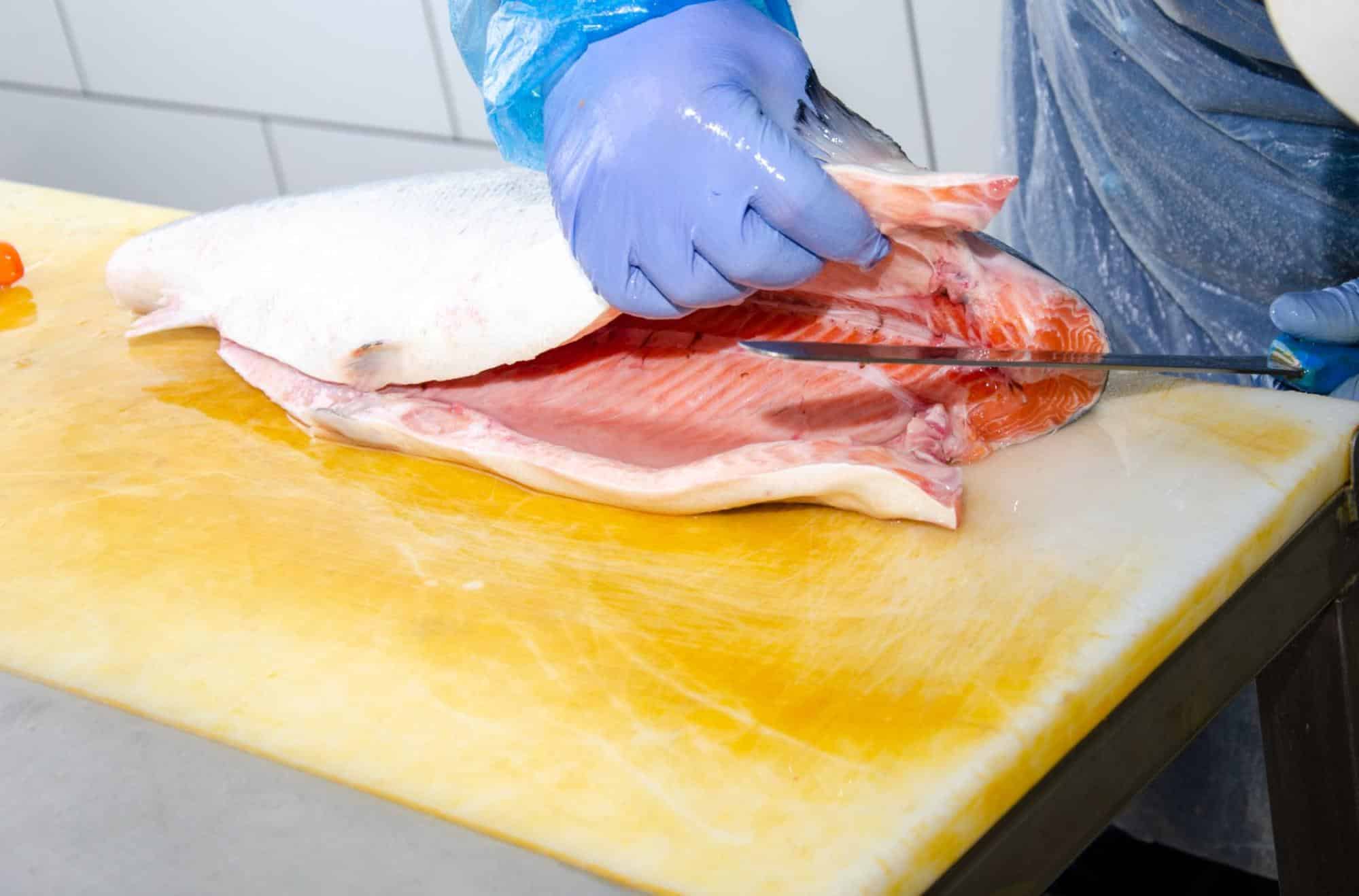 Dog-friendly fish meat being prepared on a yellow cutting board.