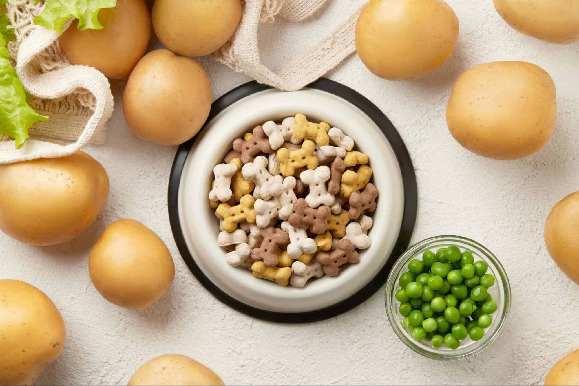 Nutritious dog food bowl with bone-shaped kibble, surrounded by fresh potatoes and green peas.