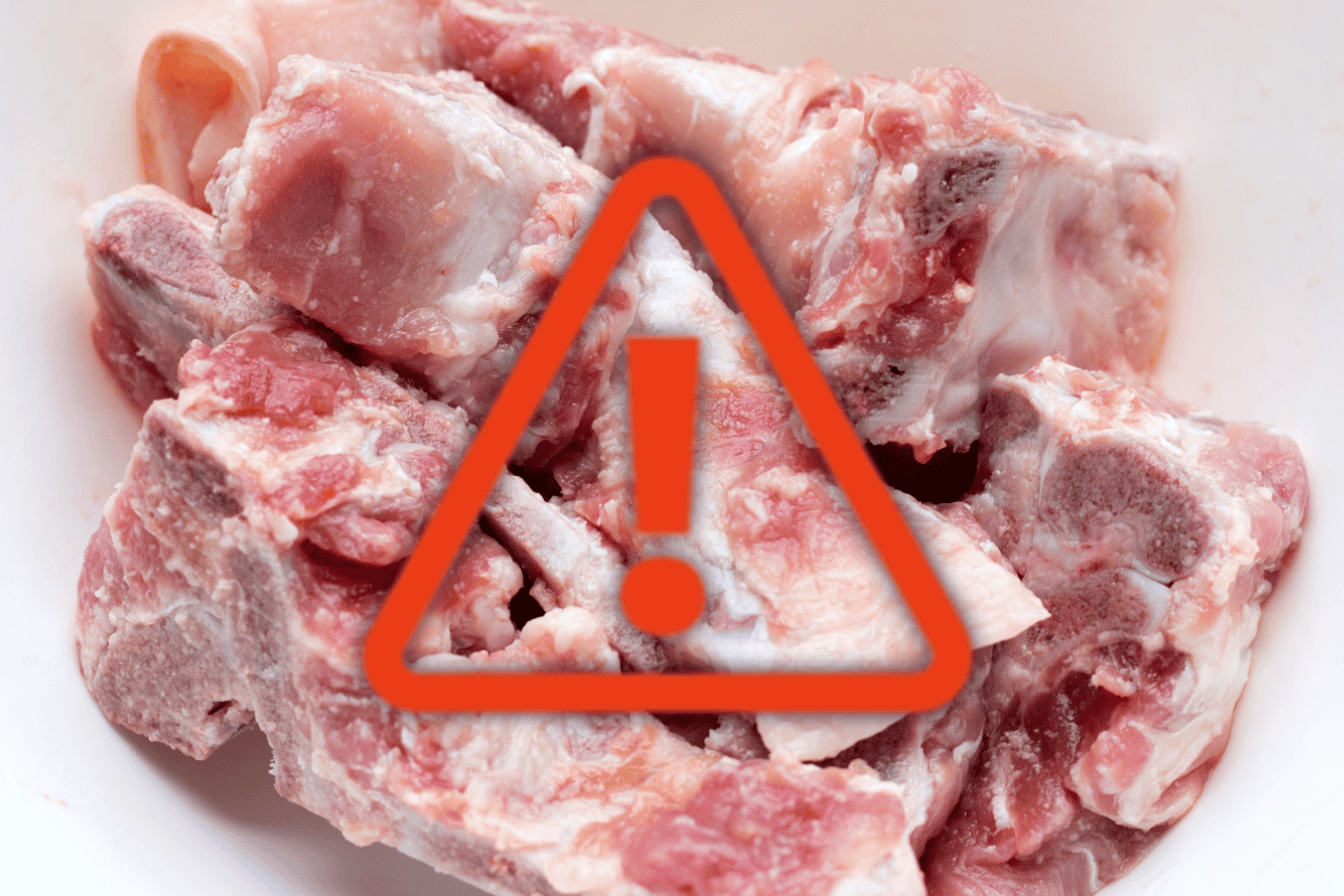 Raw pork meat with caution icon overlay, emphasizing safety in pet food preparation.