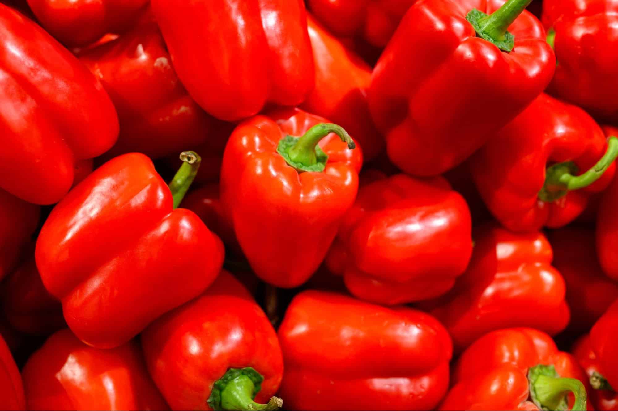 Bright red, fresh bell peppers with green stems, perfect for healthy recipes.