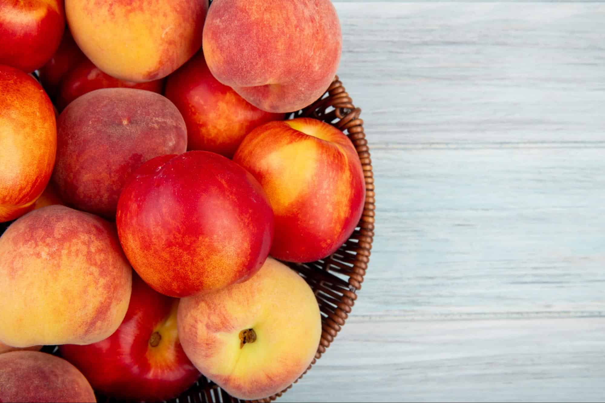 Fresh peaches in a woven basket for healthy snacking.