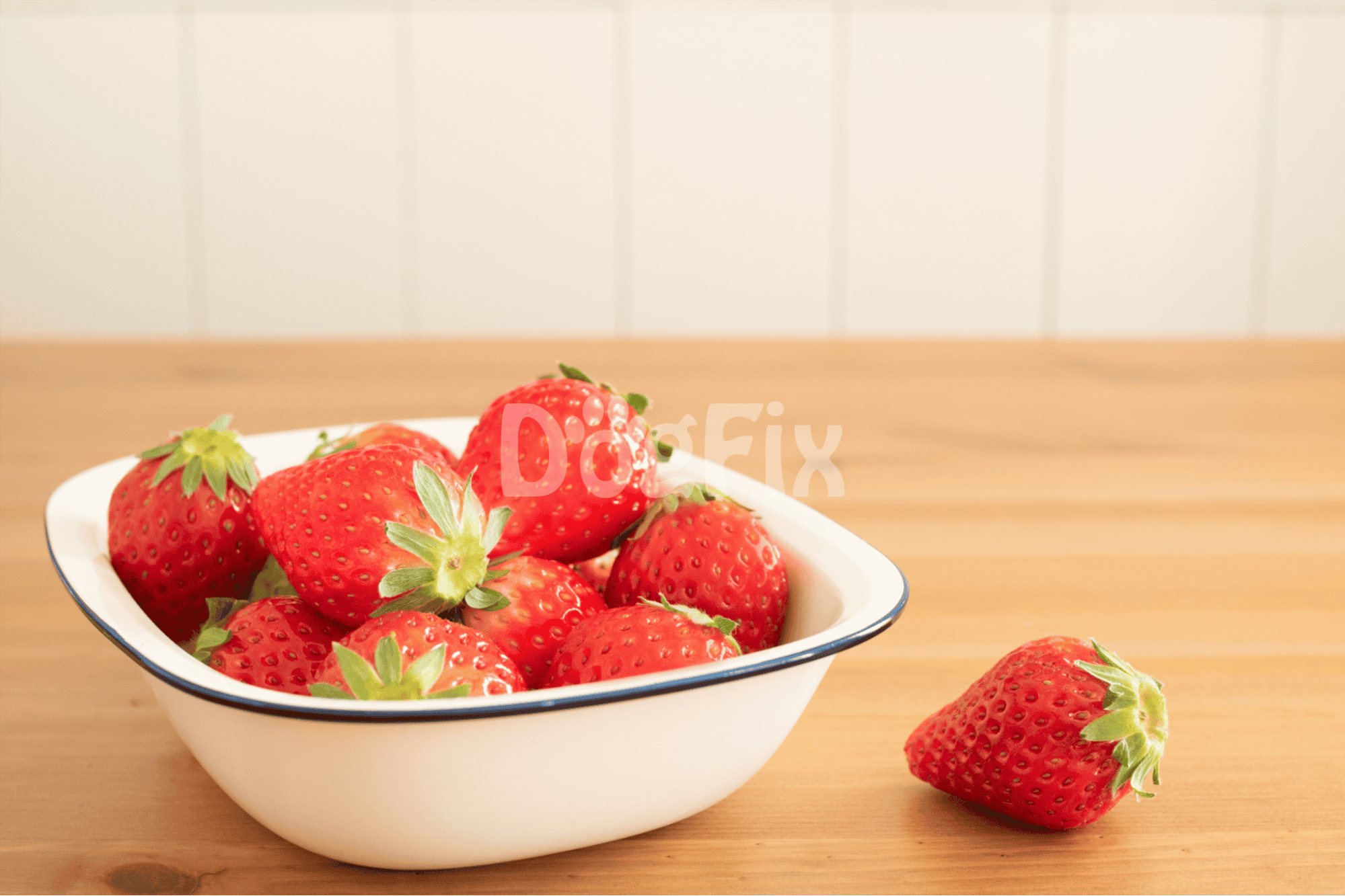 Bright, fresh strawberries in a bowl, perfect for healthy dog treats or snacks, on a wooden surface.