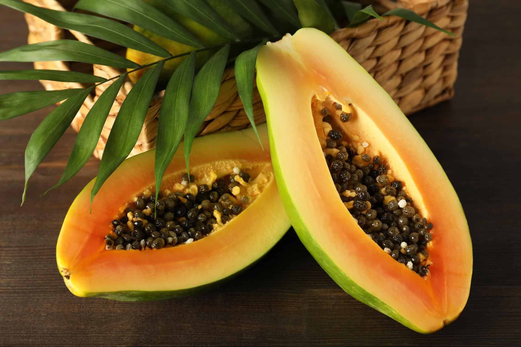 Fresh ripe papaya with seeds on dark wooden background.