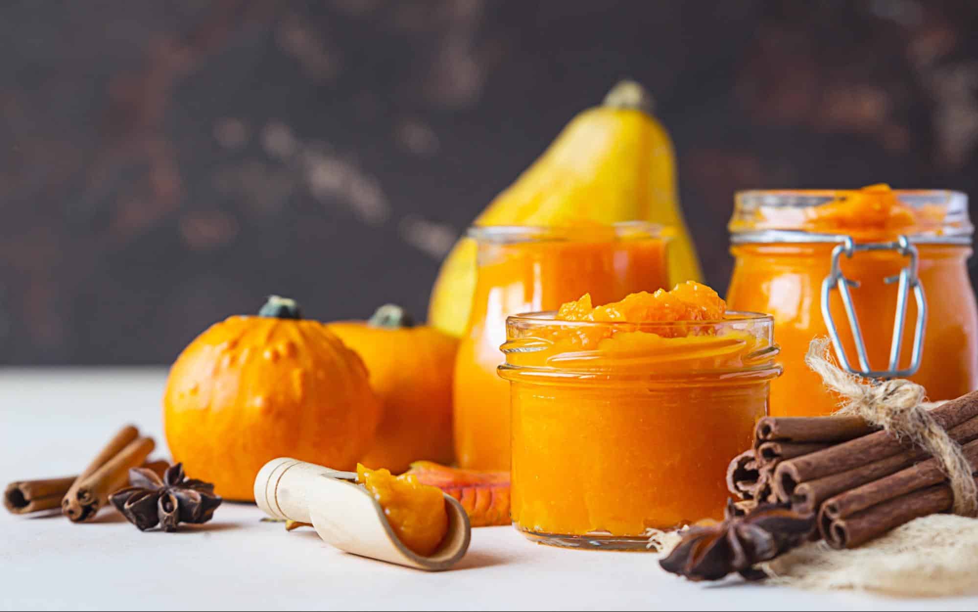 Delicious pumpkin puree jars with cinnamon sticks and fresh pumpkins for homemade dog treats.
