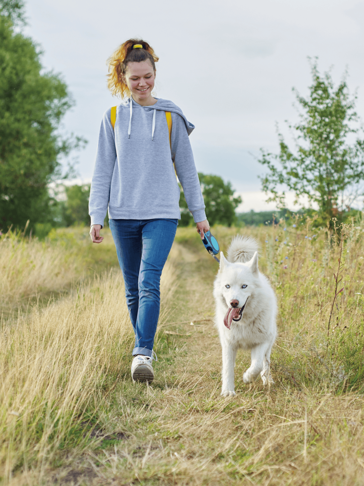 Happy young woman walking her Siberian Husky outdoors.