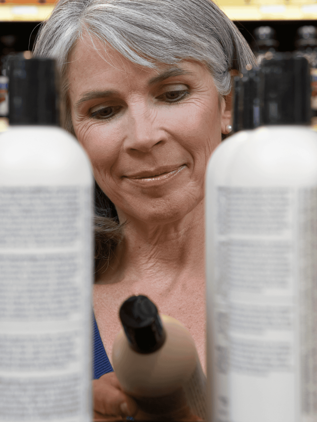 Senior woman choosing vitamins and healthcare products in a drugstore aisle.