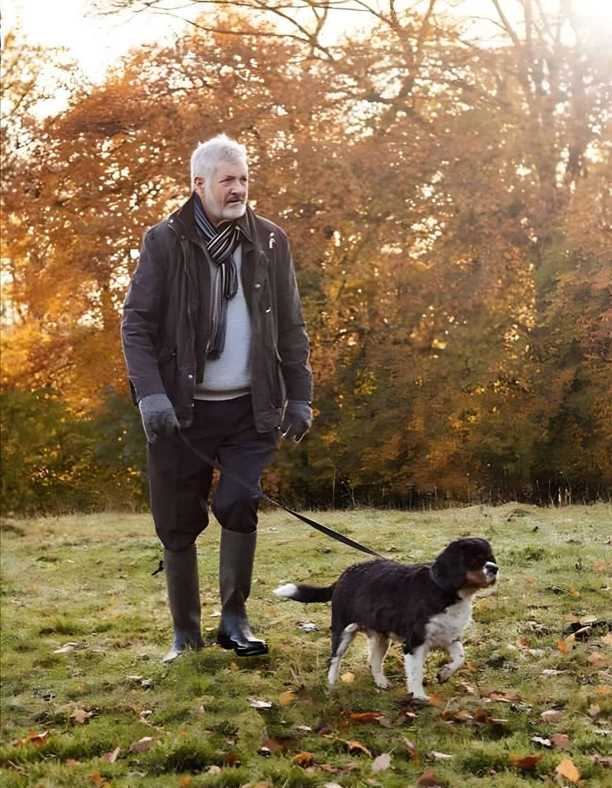 Dog on leash with owner in fall landscape.
