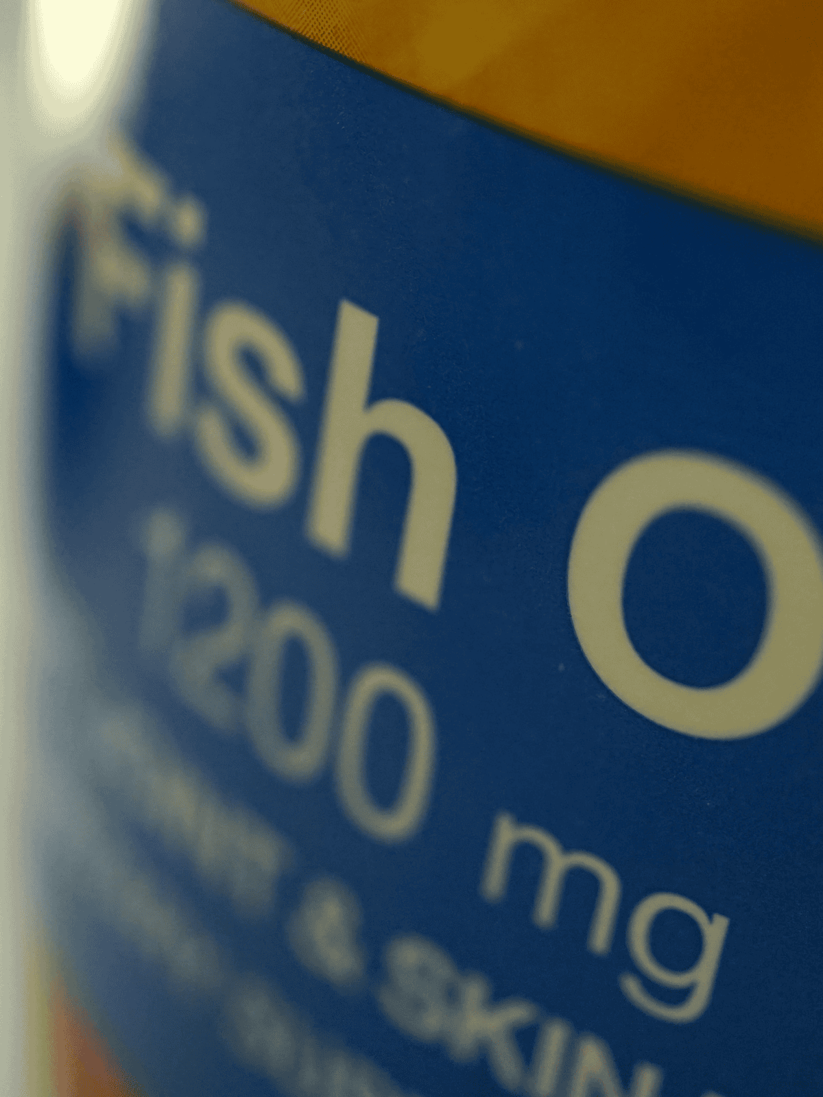 Close-up of blue fish oil supplement bottle label with text "Fish Oil 1200 mg" and "Omegas".