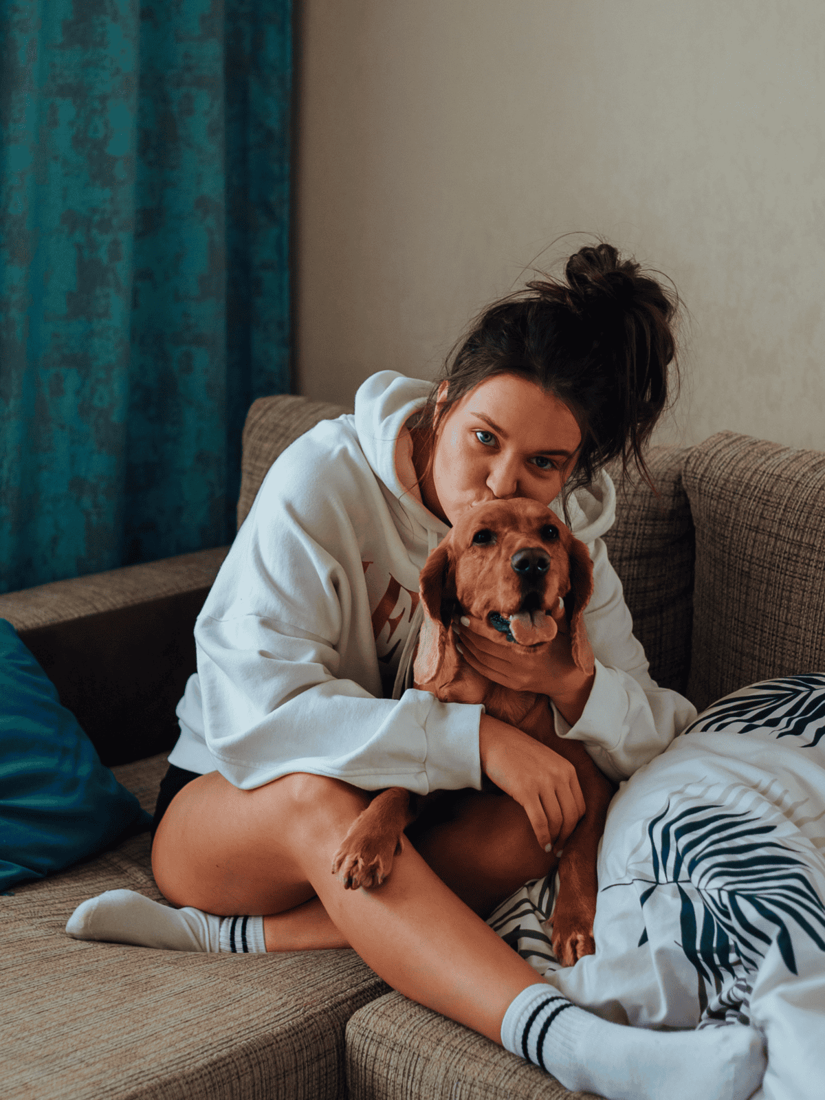 Adorable woman cuddling her playful golden retriever at home.