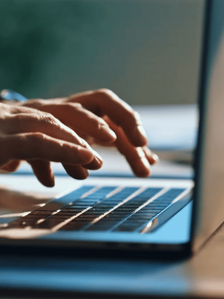 Hands typing on a laptop keyboard, writing or working from home with a dog.