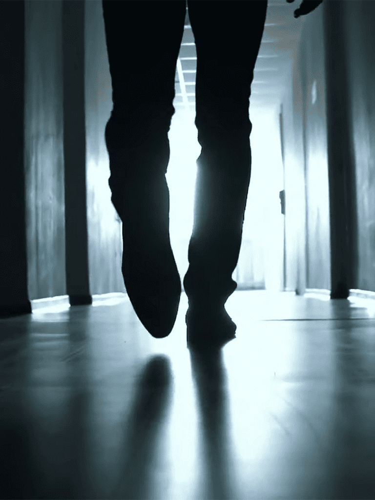 Backlit silhouette of a person walking down a hallway.