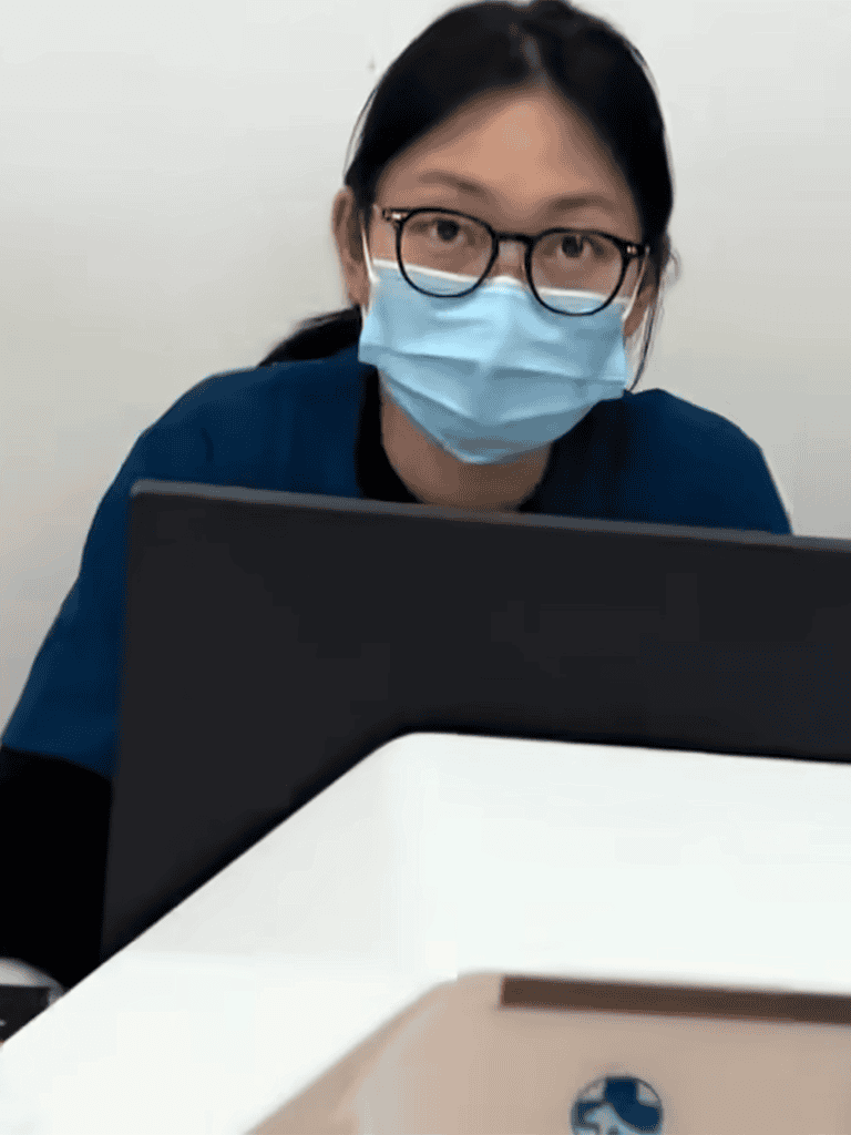 Person wearing face mask and glasses using a computer at work.