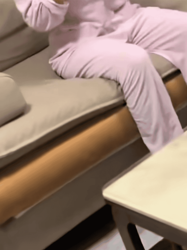 Comfortable beige couch with pink blanket, perfect for relaxing.