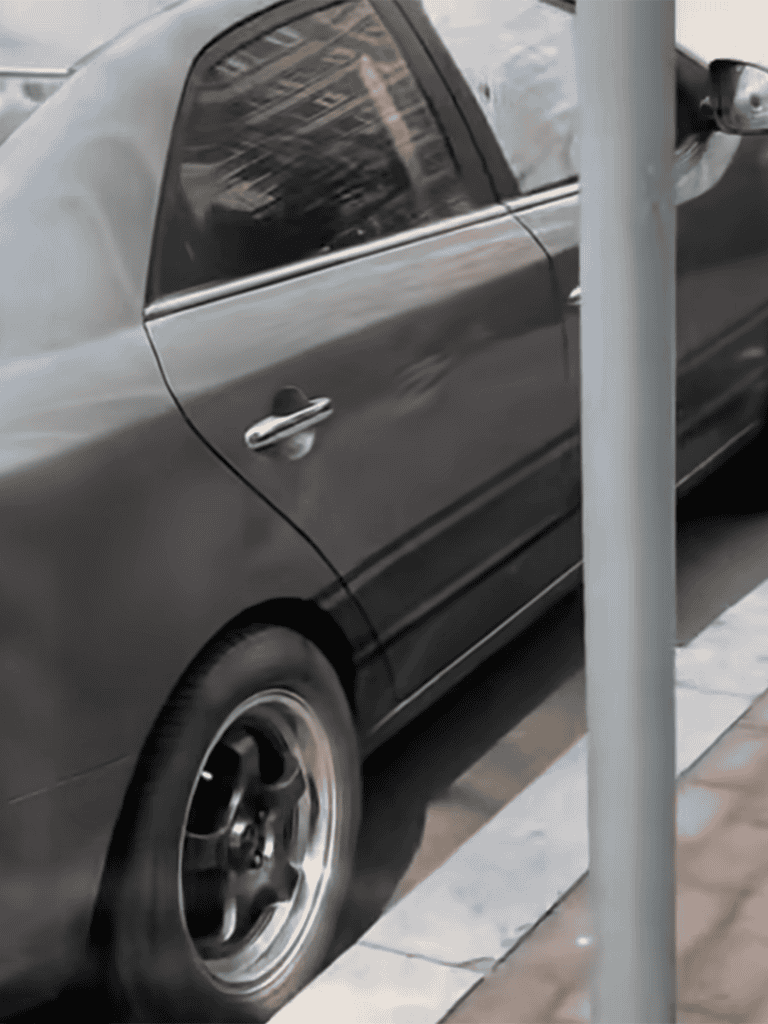 Compact black sedan parked on city street.